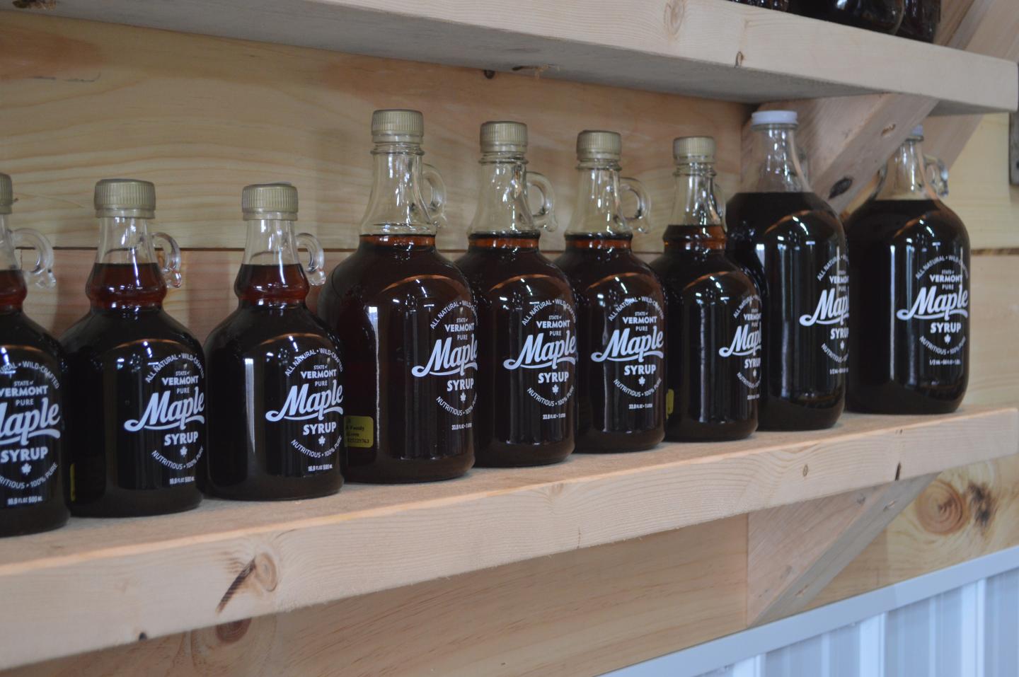 Bottles of maple syrup on a wooden shelf.