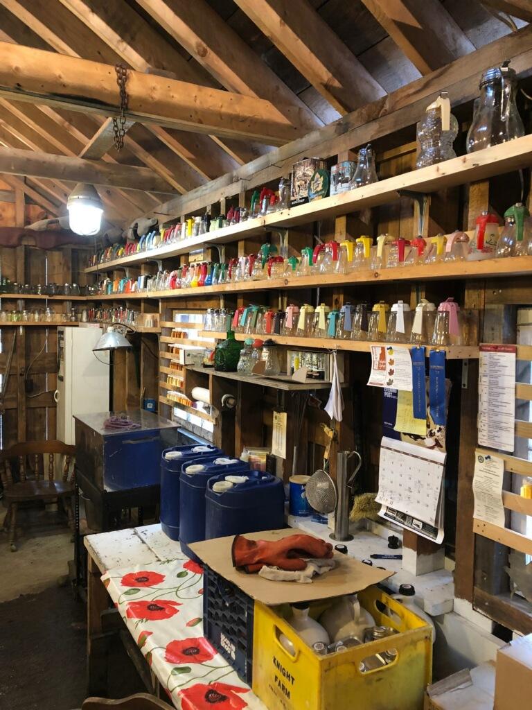 Wooden shed interior with shelves of colorful jars and boxes.