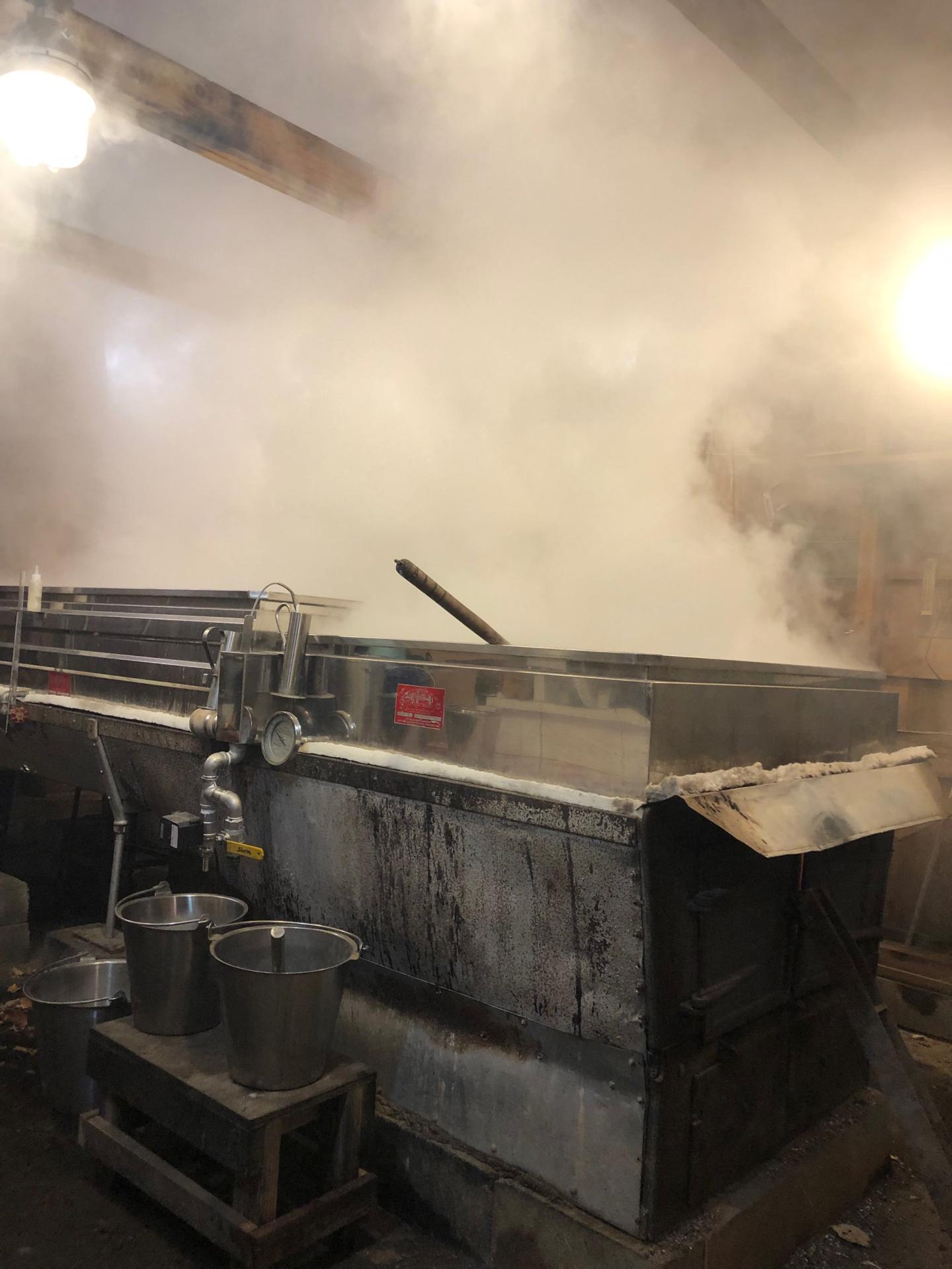 Steam rising from a large metal vat in an industrial setting.