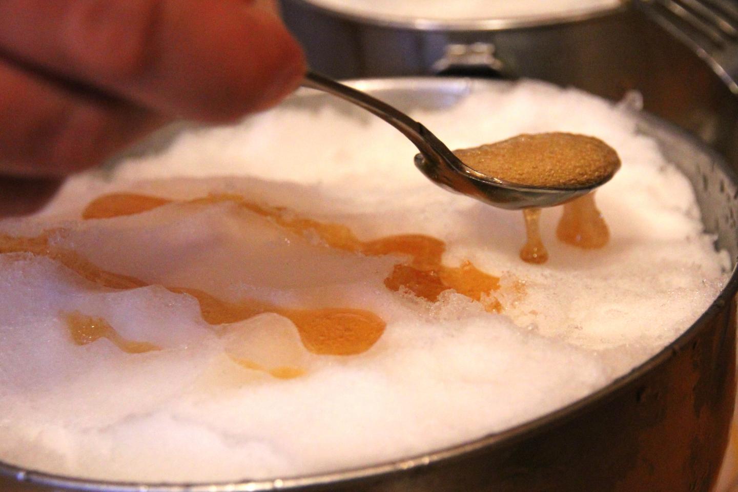 Snow with syrup being drizzled from a spoon.