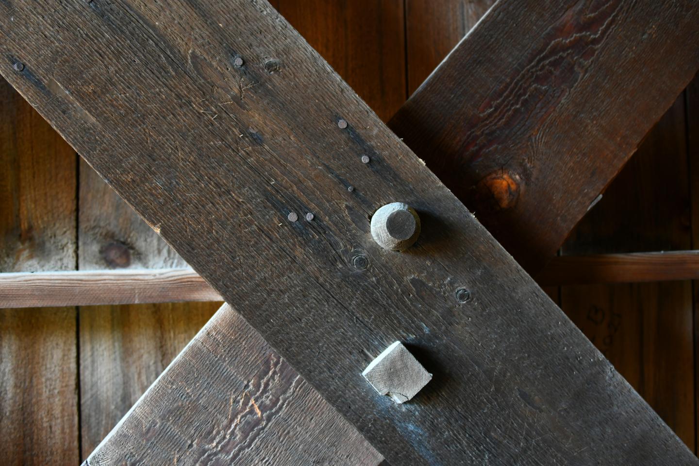 Wooden beams intersecting with bolts, close-up view.
