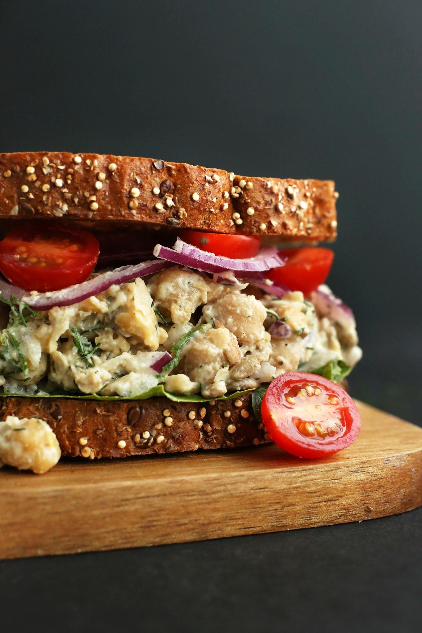 Chickpea salad sandwich with tomato and onion on seeded bread.