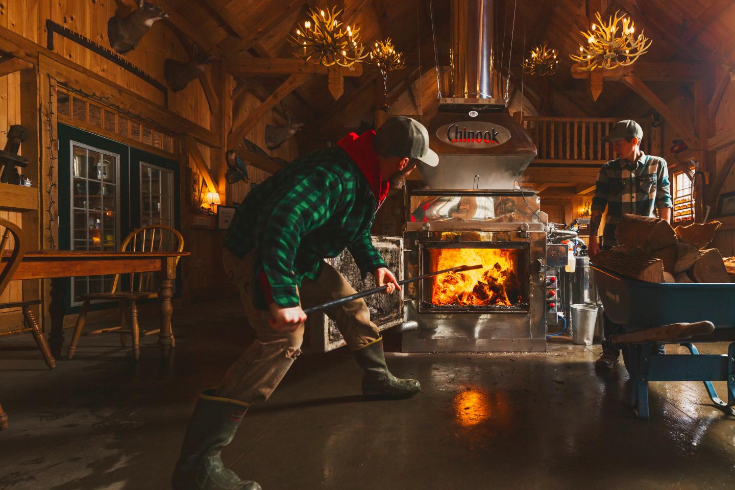 Cozy cabin with a wood-burning stove and people tending the fire.