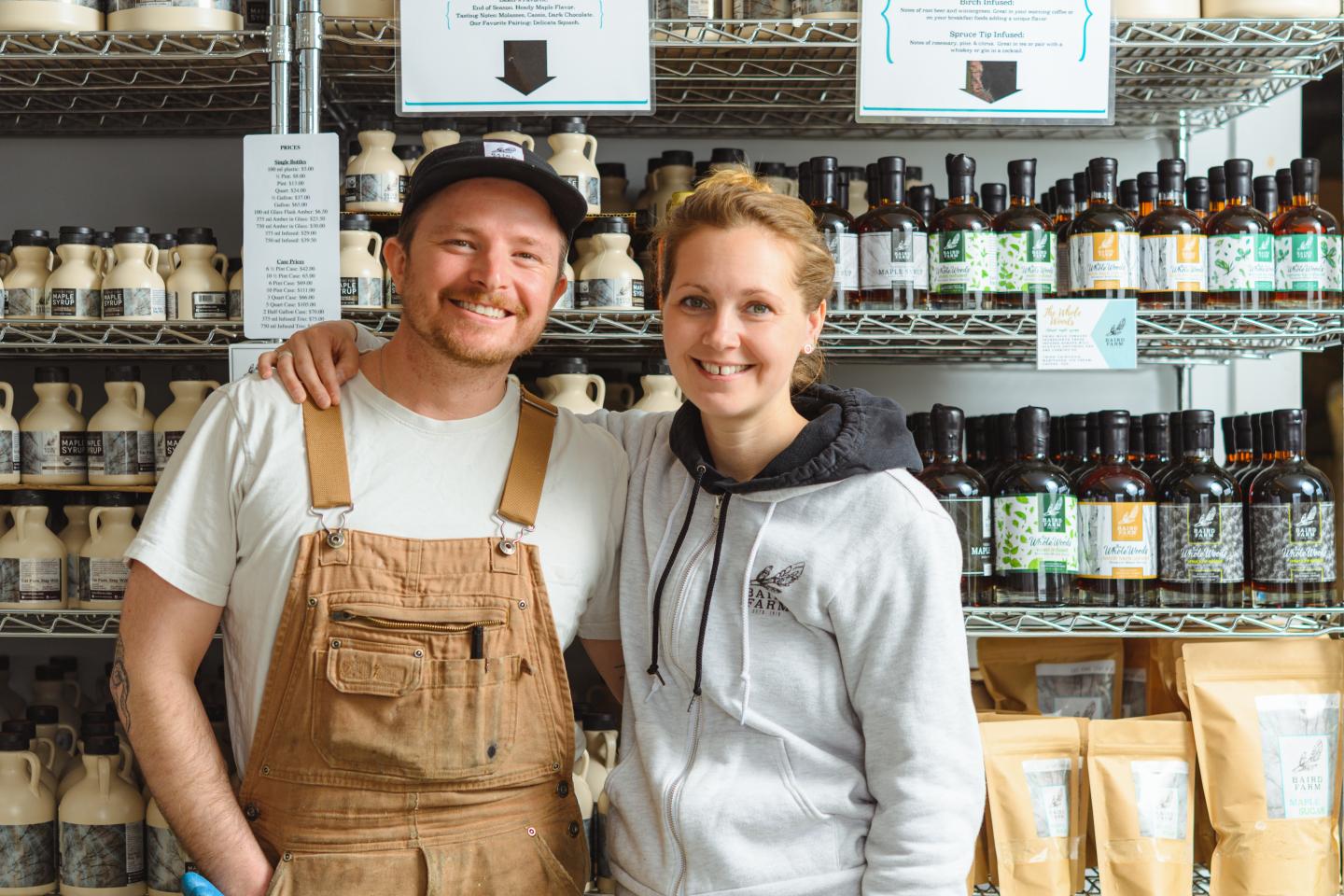 Two people smiling in a store, with products on shelves behind them.