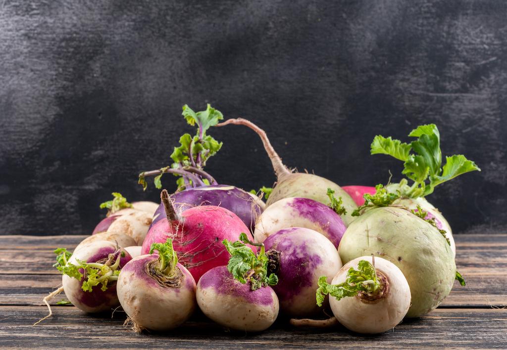 Turnips with greens on a wooden surface.