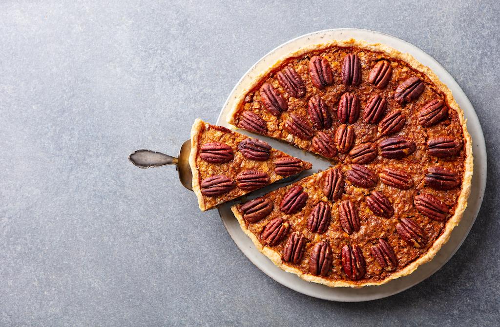 Pecan pie with a slice being served on a pie server.