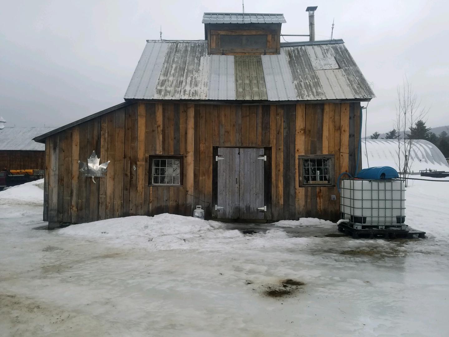 Wooden building on icy ground, overcast sky.