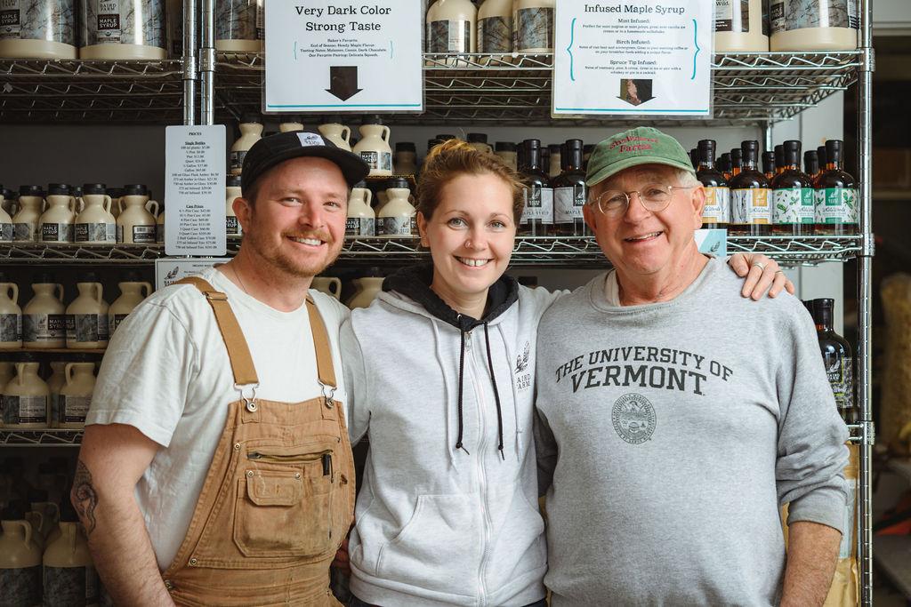 Three smiling people standing together in a store with shelves of products.
