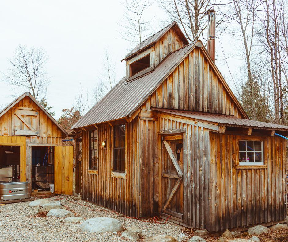 Rustic wooden cabins surrounded by bare trees in a rural setting.