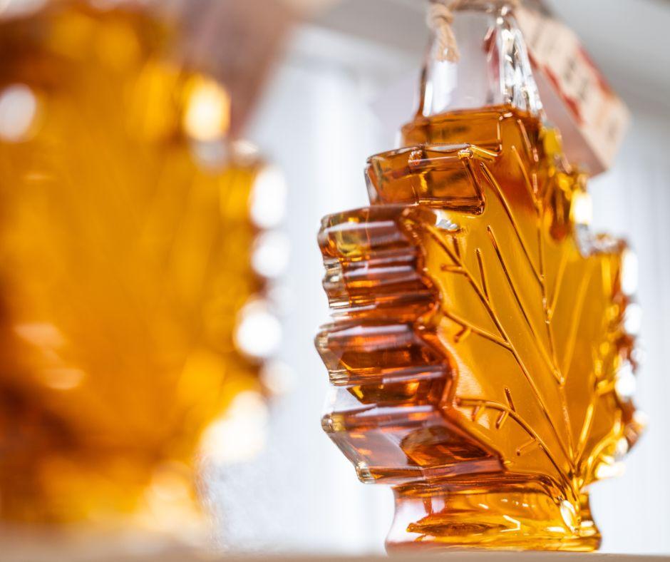 Maple syrup bottles shaped like leaves, filled with amber syrup.