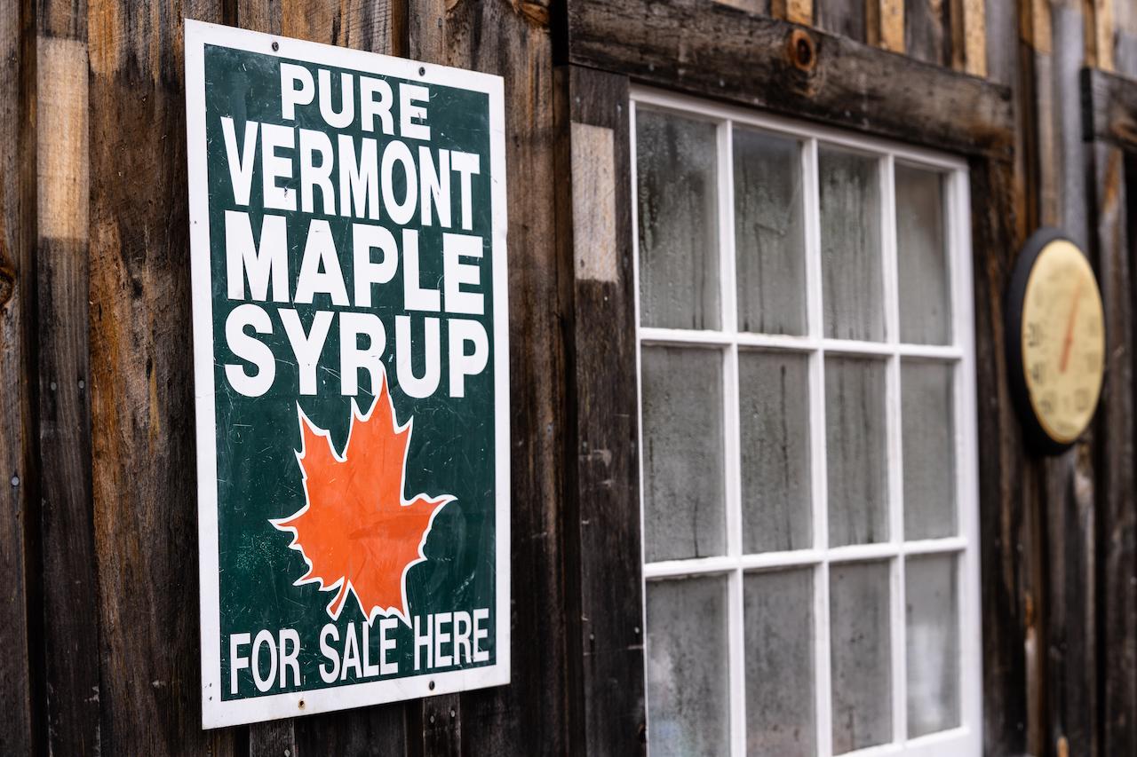Wooden wall with a sign for Vermont maple syrup and a window.