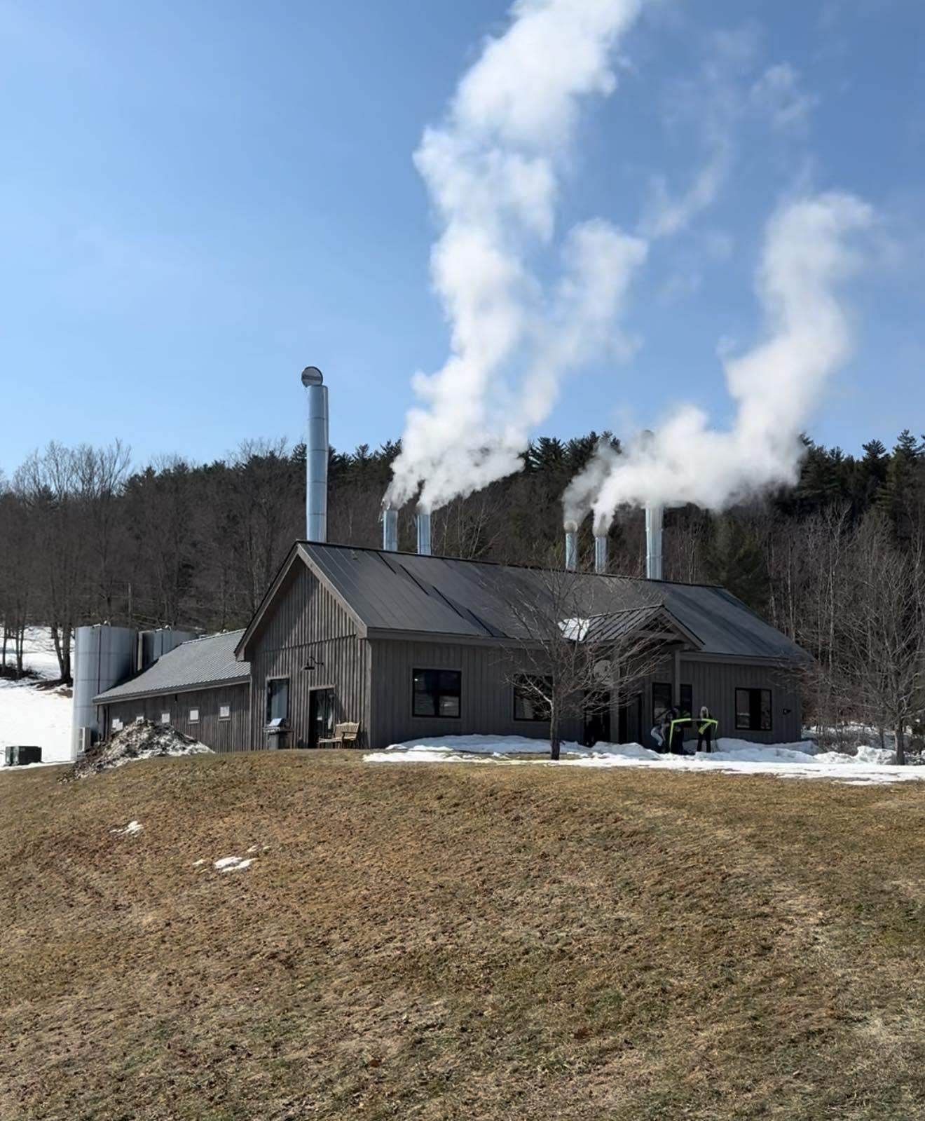 Sugarhouse with steam rising against a blue sky.