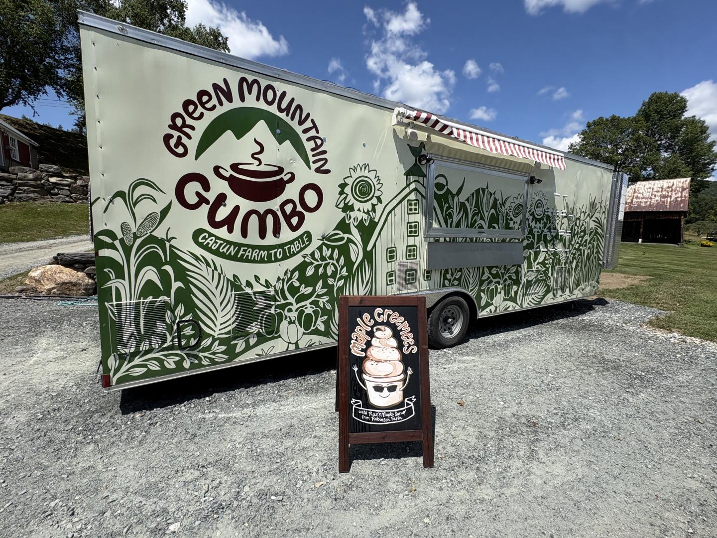 Food truck with "Green Mountain Gumbo" logo and a chalkboard sign outside.