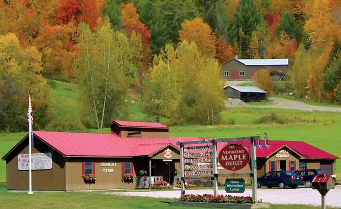 Rural store in autumn with red roofs, surrounded by colorful trees.