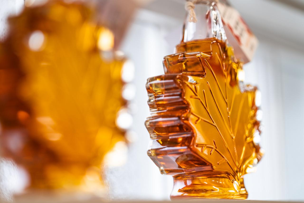Maple leaf-shaped glass bottles filled with amber liquid.